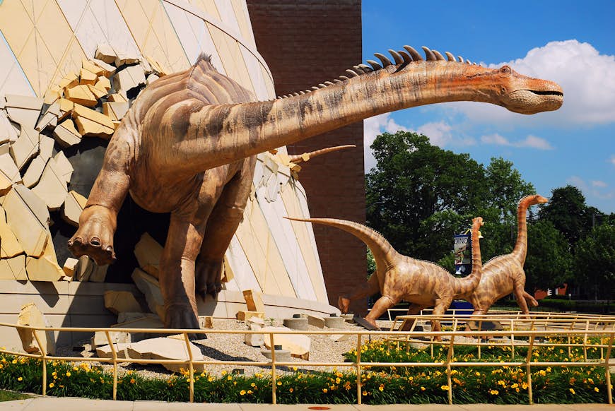 A huge dinosaur model appears to burst through the walls of a building at the children's museum in Indianapolis