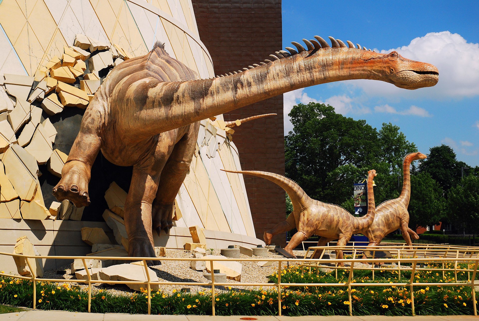 A huge dinosaur model appears to burst through the walls of a building at the children's museum in Indianapolis