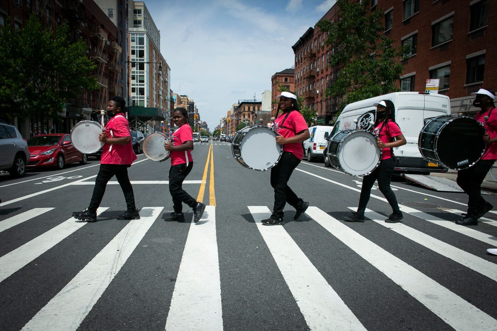 A marching band crosses the street June 19, 2021 in Harlem, New York, New York, USA