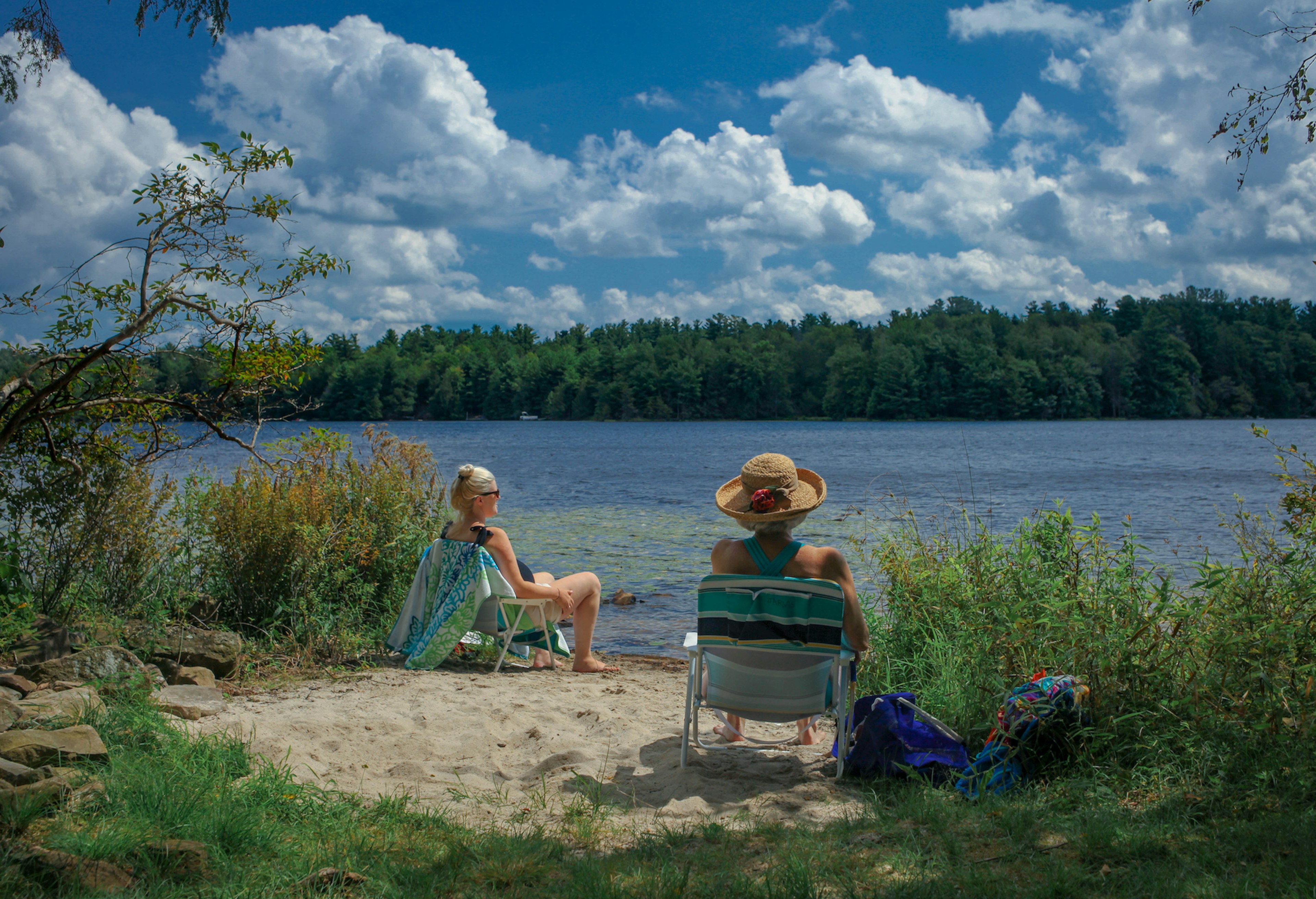 Pocono Lake, PA USA - April 6, 2021: Two Women Sitting by Pocono Lake to Cool Off From Summer Heat; Shutterstock ID 1950967123; your: Brian Healy; gl: 65050; netsuite: Lonely Planet Online Editorial; full: Best time to visit the Poconos