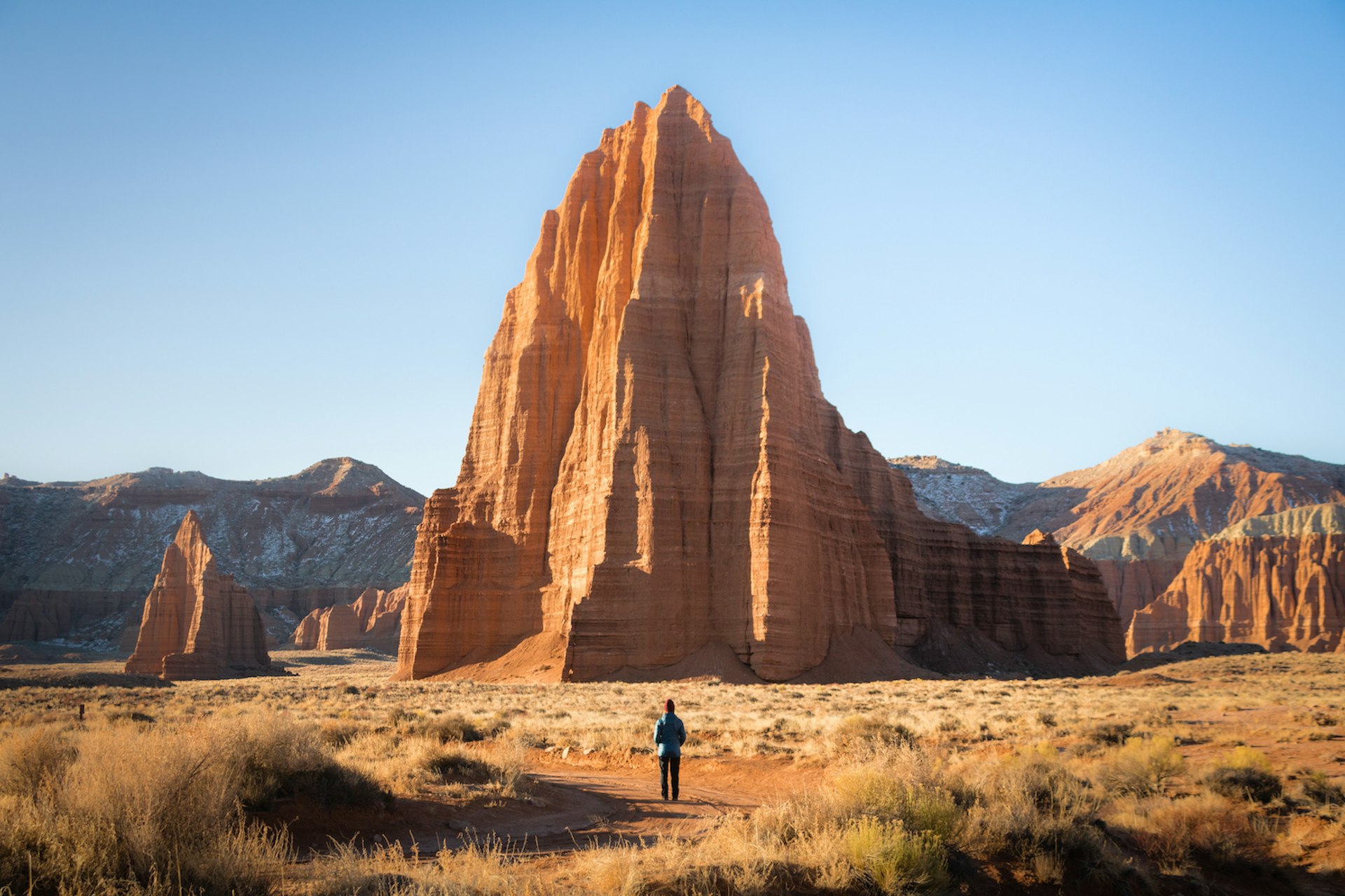 A man stands in front of the Temple of the Sun rock formation, Capitol Reef National Park, Utah, USA