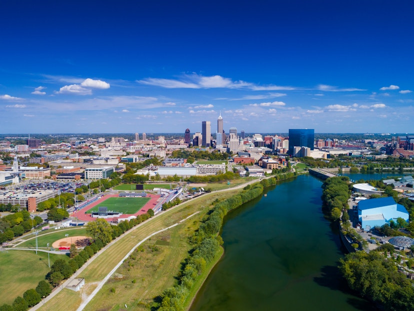 Indianapolis aerial view with Downtown Indianapolis and a blue sky with clouds in the background, and White River and Indiana University - Purdue University Indianapolis(left) and Indianapolis Zoo (right) in the foreground.