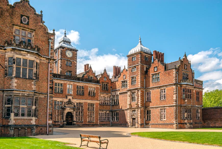 A grand Jacobean-style redbrick mansion with a large central clocktower 
