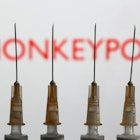 Medical syringes are seen with 'Monkeypox' sign displayed on a screen in the backgound in this illustration photo taken in Krakow, Poland on May 26, 2022. (Photo by Jakub Porzycki/NurPhoto via Getty Images)