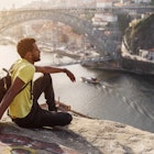 Traveler man enjoying city view in Porto, famous iron bridge and Douro rive on background