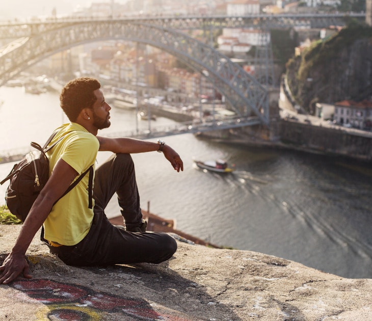 Traveler man enjoying city view in Porto, famous iron bridge and Douro rive on background