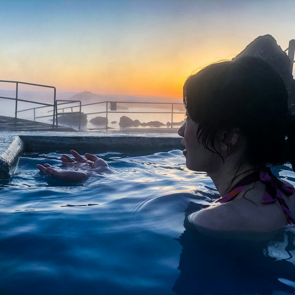 April 2018: Woman taking a bath in the hot spring pool of Myvatn Nature Bath during sunset.