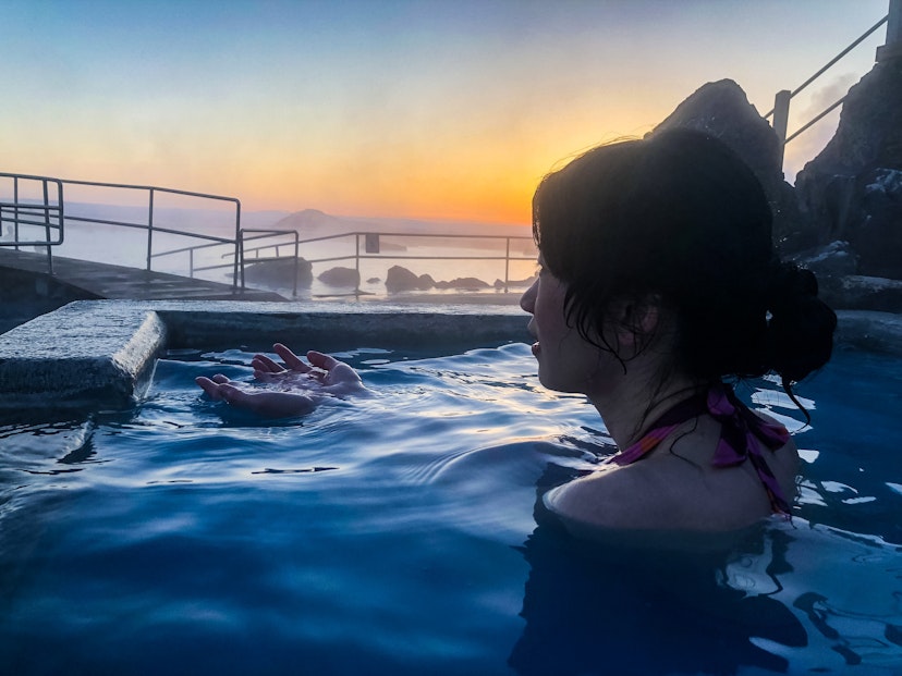 April 2018: Woman taking a bath in the hot spring pool of Myvatn Nature Bath during sunset.