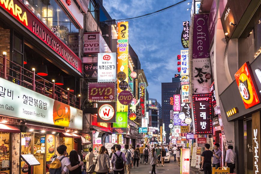 Les gens se promènent la nuit dans la rue piétonne du quartier commerçant et de divertissement de Myeong-dong