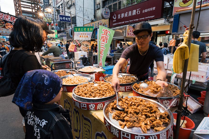 Man serving food at Raohe Street Night Market in Taipei