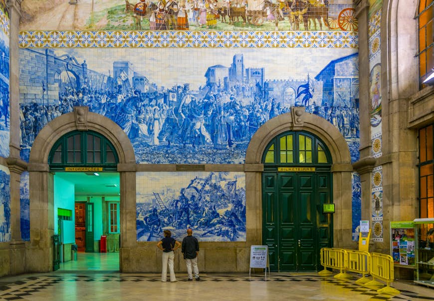 People looking up at the azulejos mosaics in Porto Central Station