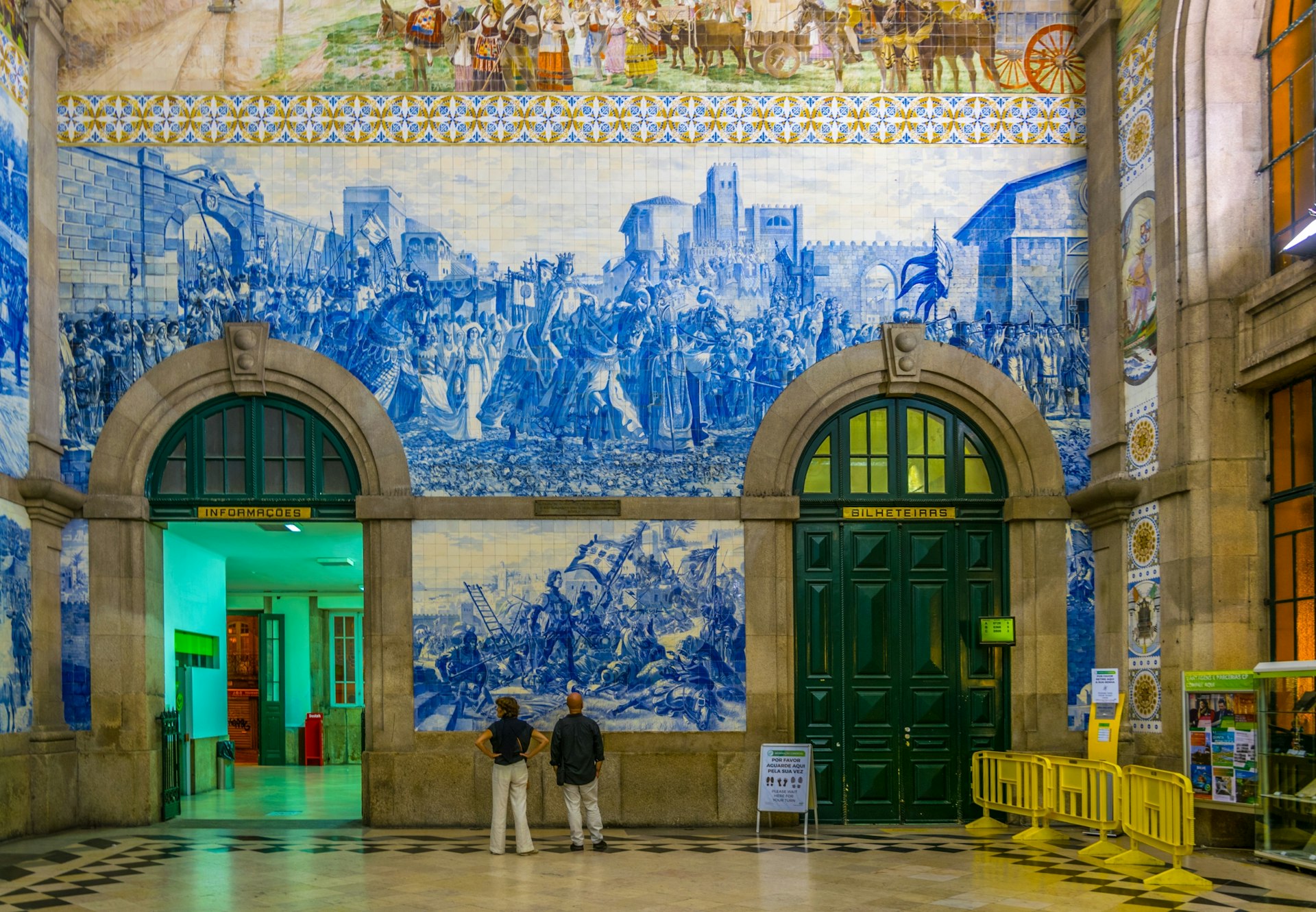People looking up at the azulejos mosaics inside the main train station at Porto