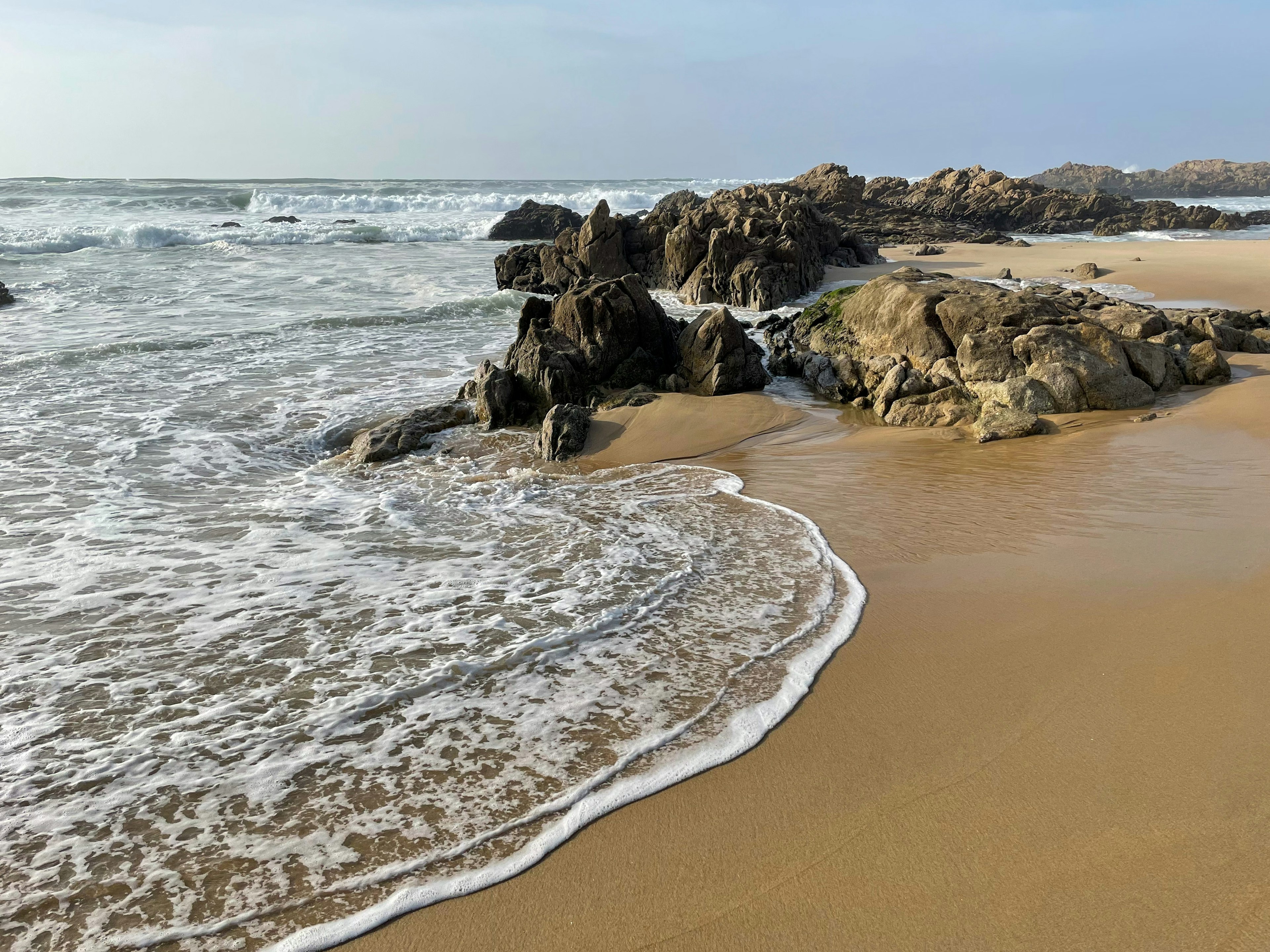 Stunning view of sandy beach with yellow rocks and Atlantic ocean in Matosinhos Beach in Portugal