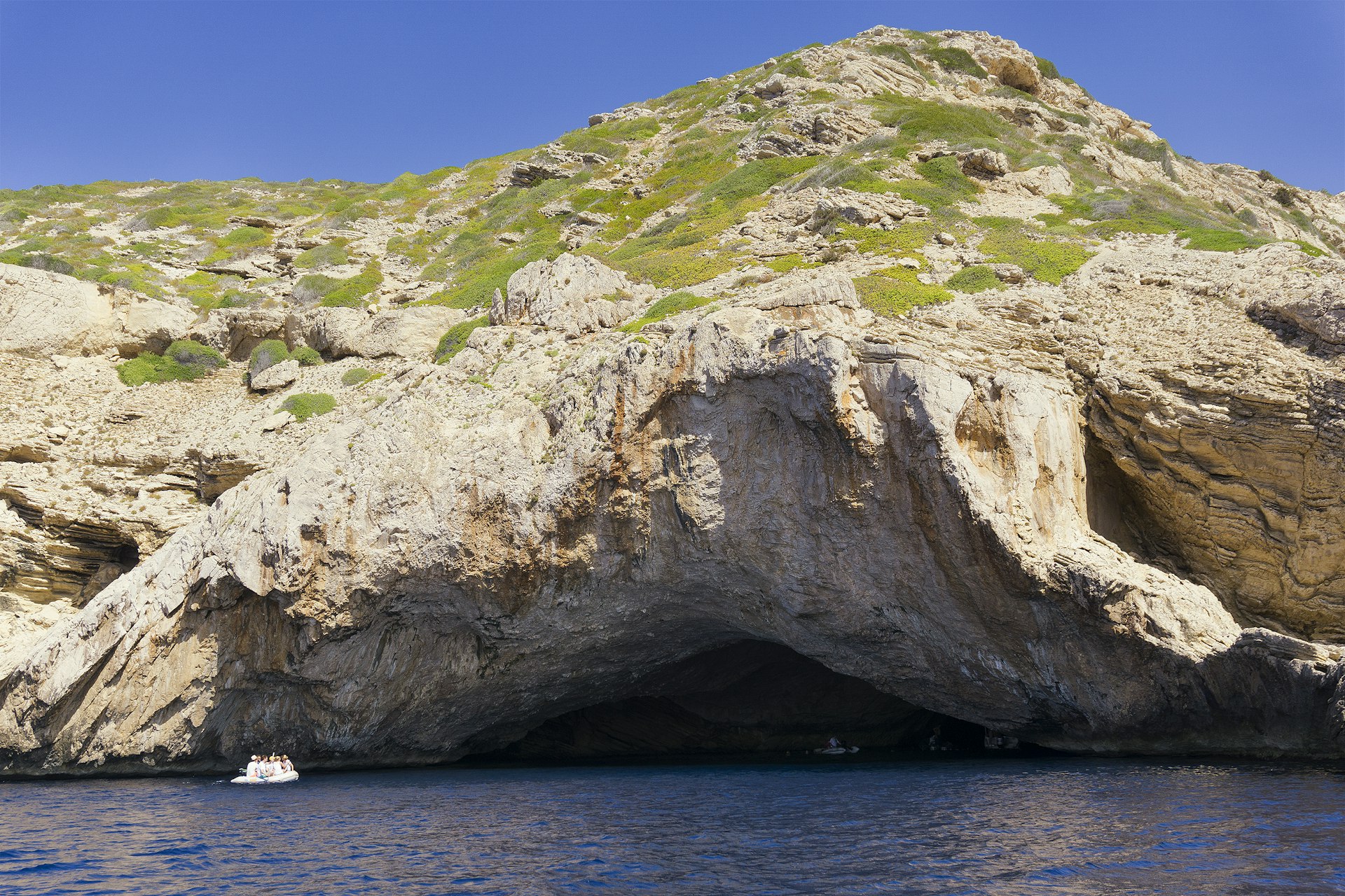 A small boat explores the picturesque coast of Cabrera Island