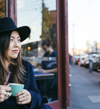 Woman with a hat taking a coffee in Fitzroy, in Melbourne. Street style.