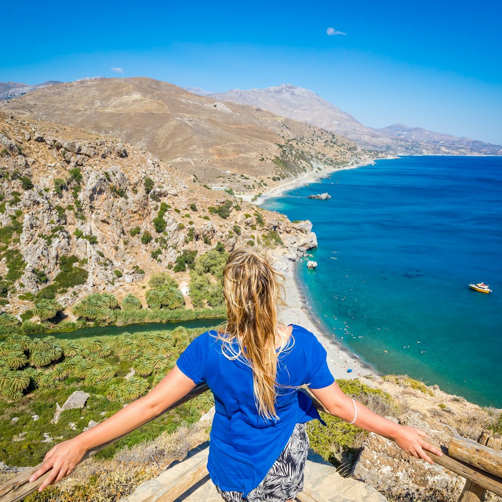 A woman admires Preveli Beach on Crete from the hillside