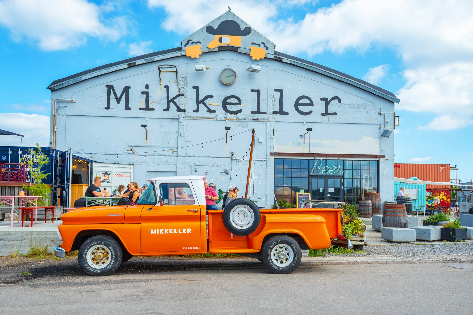 An orange retro car parked outside the Mikkeller bar at Reffen street food market.