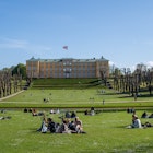 People enjoying the sunshine in front of the castle in Frederiksberg Gardens