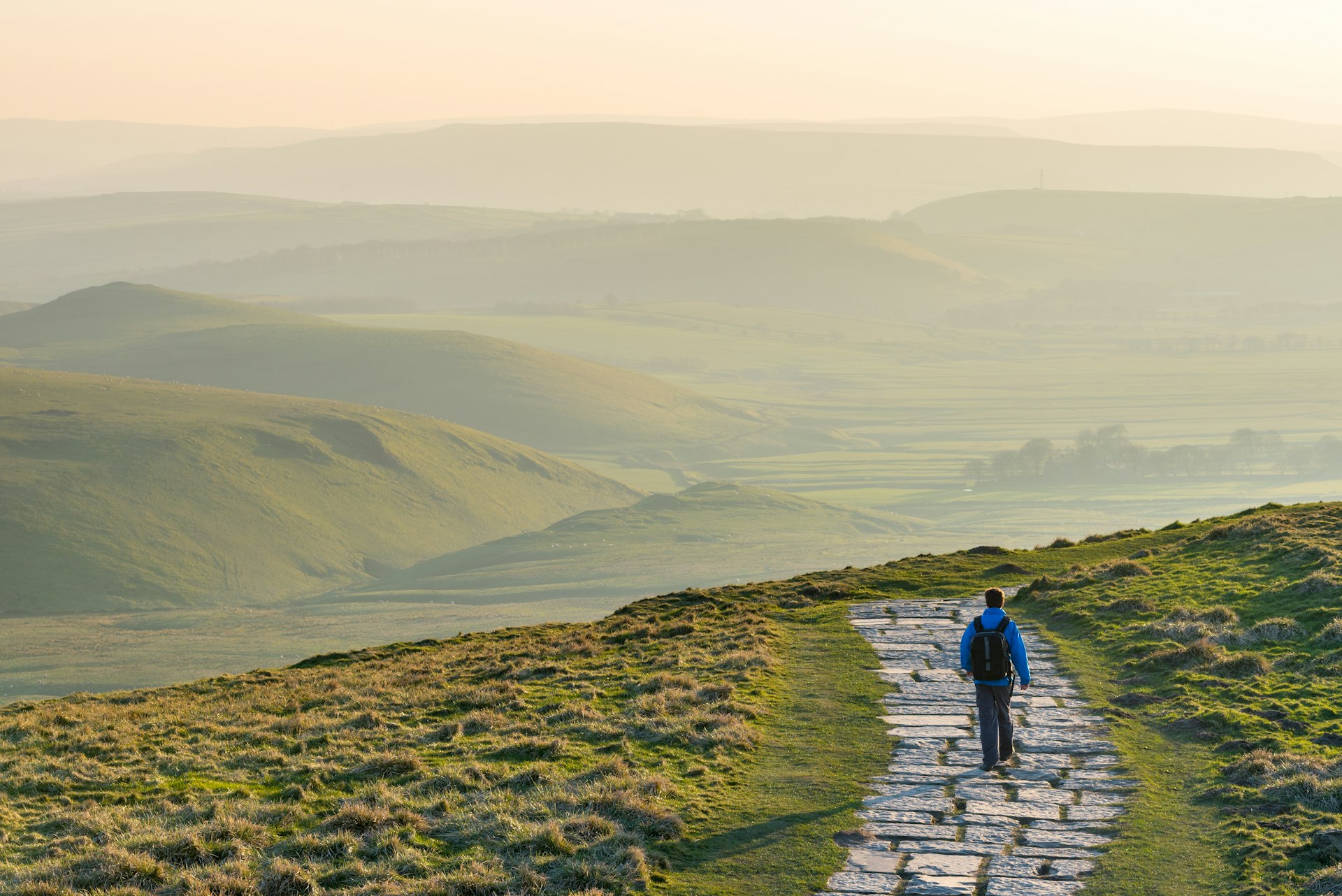 A hiker on the stone path at Mam Tor in Peak District National Park, England