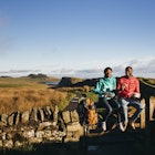 Two hikers sitting on a dry stone wall in Northumberland, England