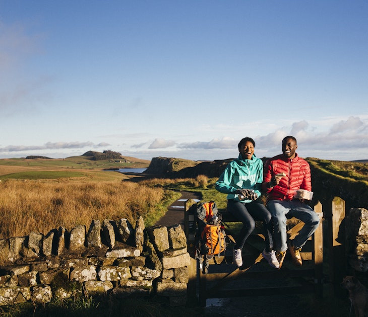 Two hikers sitting on a dry stone wall in Northumberland, England