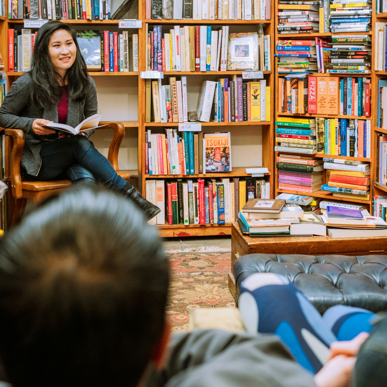 A woman reading to a small audience in an independent bookstore in San Francisco.
