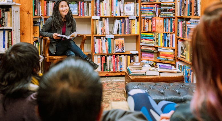 A woman reading to a small audience in an independent bookstore in San Francisco.