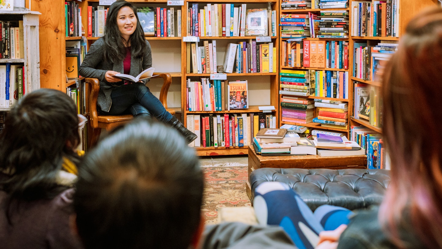 A woman reading to a small audience in an independent bookstore in San Francisco.