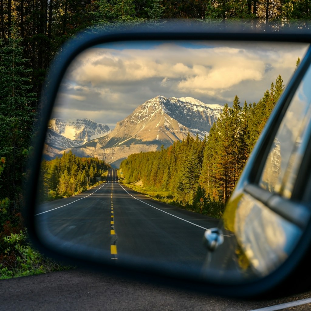 Driving through a mountain road and watching the beautiful scenery in the rearview mirror in the icefields parkway near Jasper - Driving a car through a mountain road that leads through the Canadian Rockies and watching the beautiful scenery in the rearview mirror in the icefields parkway, Jasper National Park, Alberta, Canada