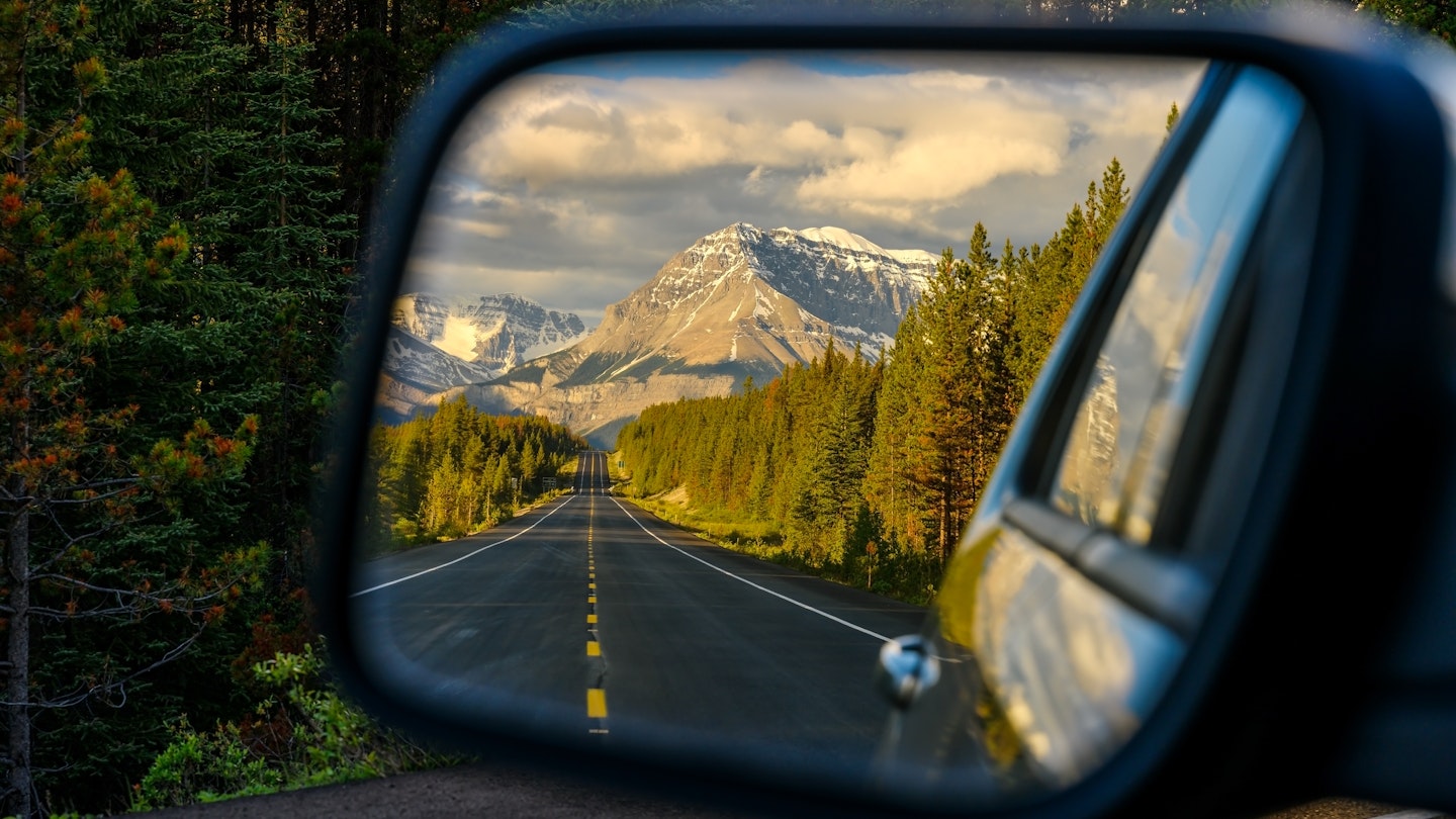 Driving through a mountain road and watching the beautiful scenery in the rearview mirror in the icefields parkway near Jasper - Driving a car through a mountain road that leads through the Canadian Rockies and watching the beautiful scenery in the rearview mirror in the icefields parkway, Jasper National Park, Alberta, Canada