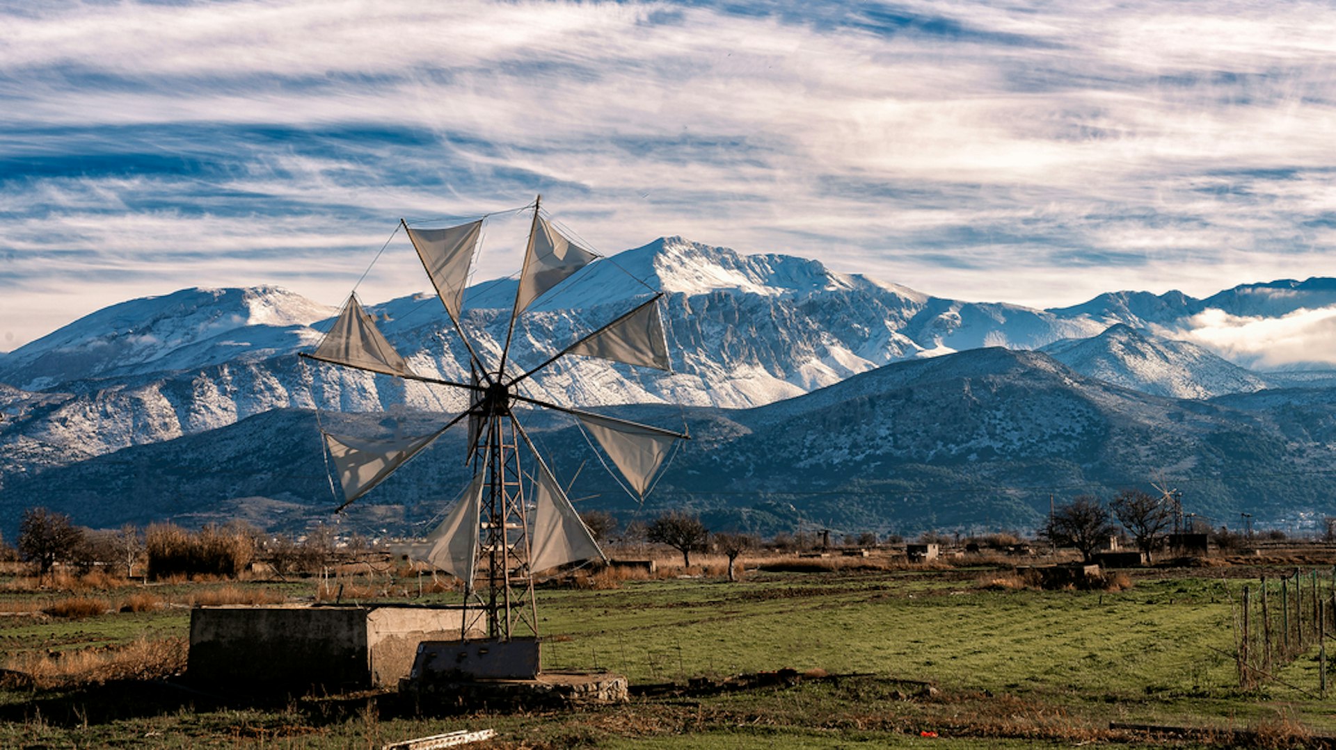 Windmills on a plateau with snow-capped mountains in the background