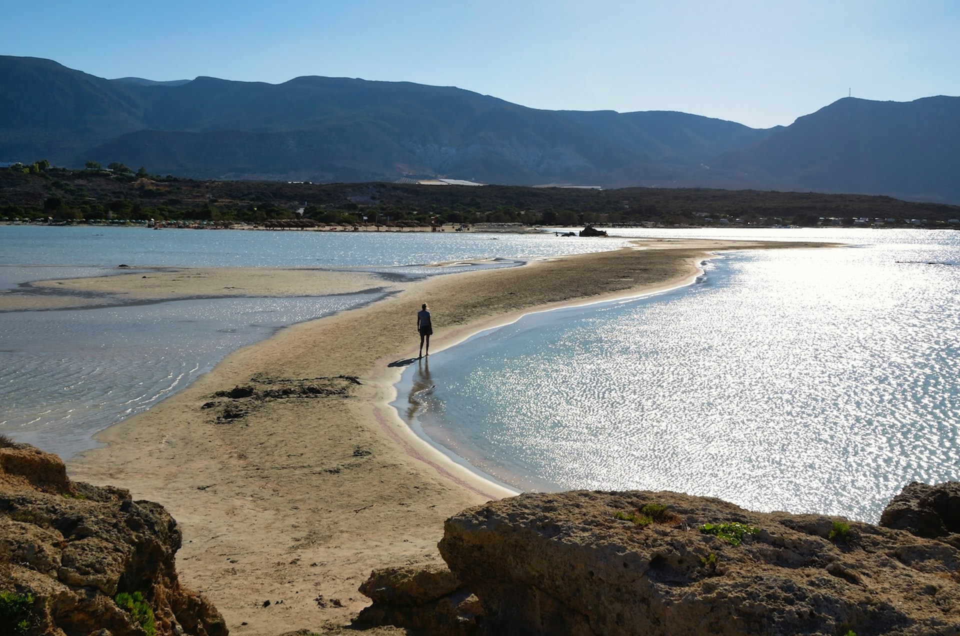 A person walks across the sandy isthmus connecting Elafonisi Beach and Elafonisi Islet, Crete, Greece