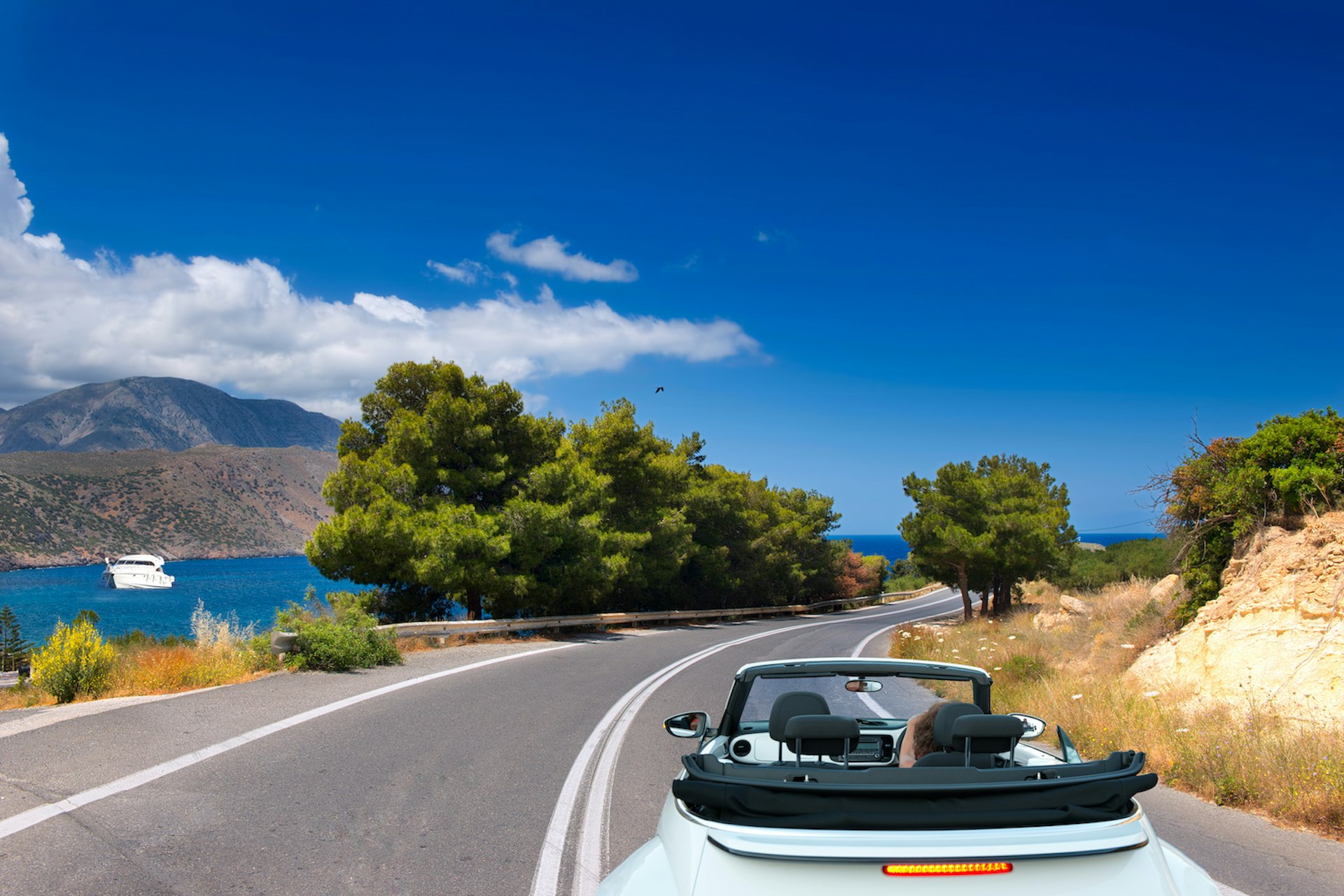 A convertible on the open road by the sea in Crete, Greece