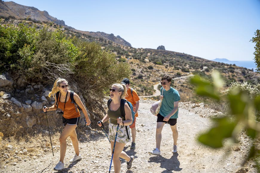A group of friends hiking up a rocky trail in the sunshine in Crete