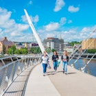 Young women cross the Peace Bridge in Derry, Northern Ireland