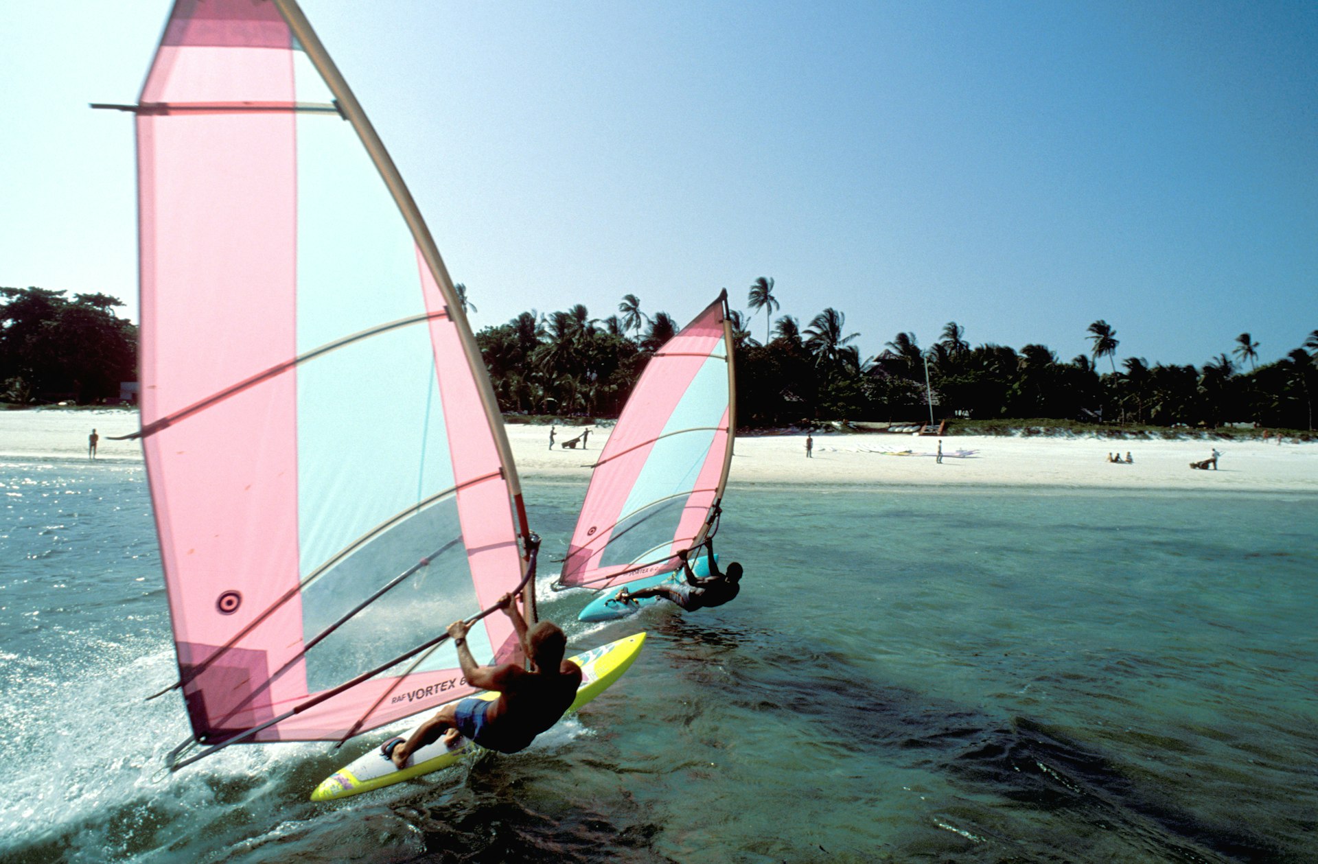 Two men windsurfing in sea off beach holiday resort near Mombasa
