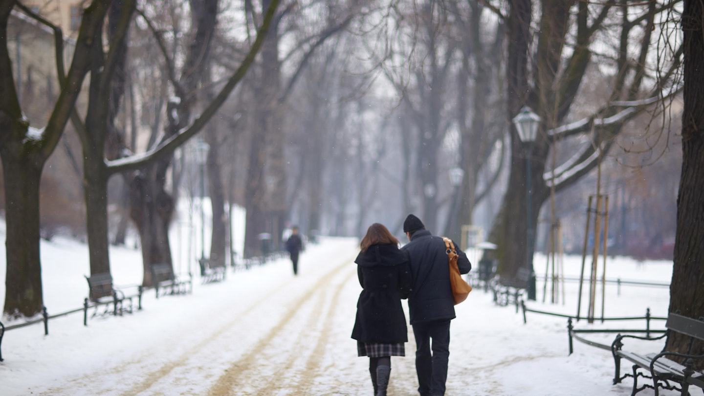 Couple walking in snow towards Wawel Hill.
