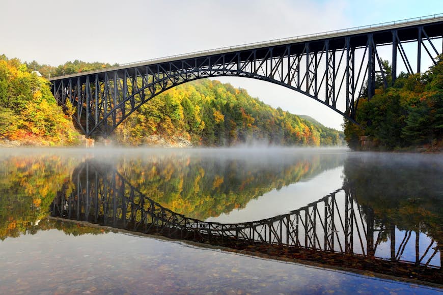 Den franska kungbron är en trespann "fribärande båge" stilbro som korsar Connecticutfloden på gränsen till städerna Erving och Gill, i Pioneer Valley i Massachusetts.  Foto taget på en dimmig morgon under den tidiga lövsäsongen.