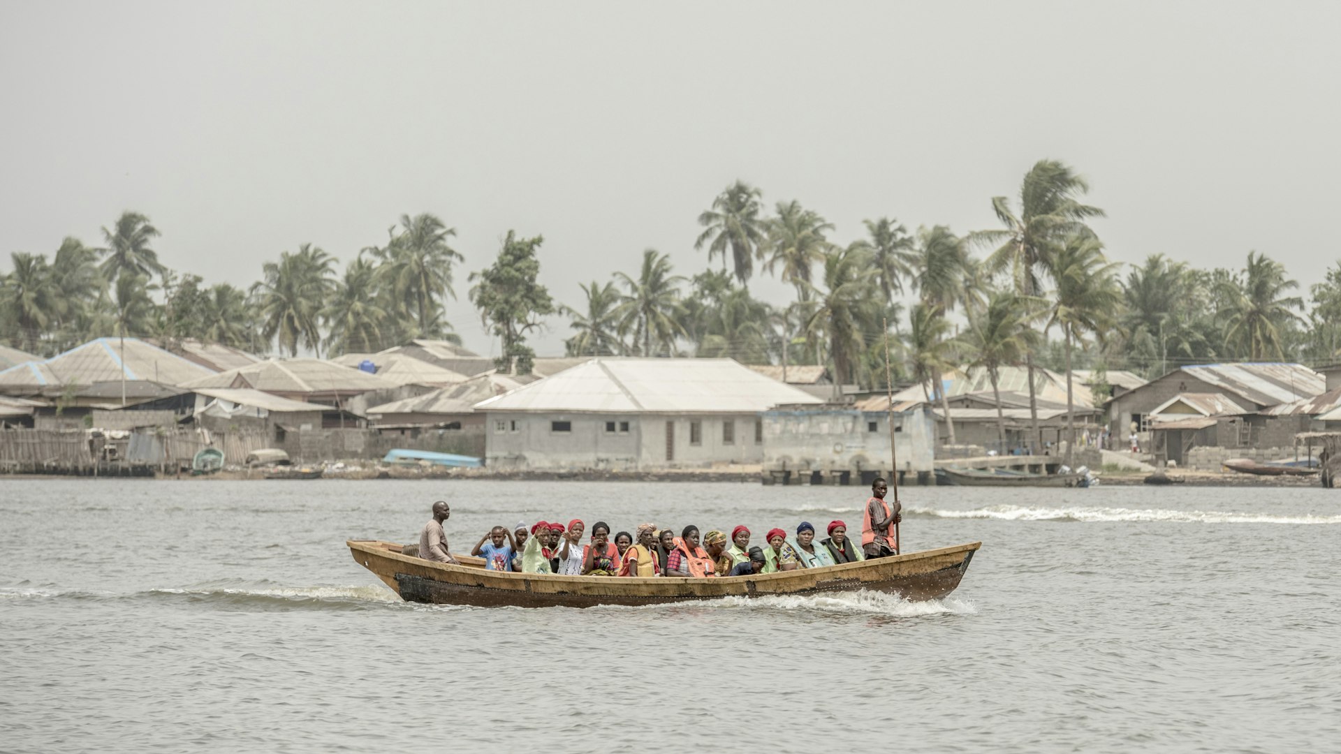 Group of people taking small ferry boat across Lagos Creek
