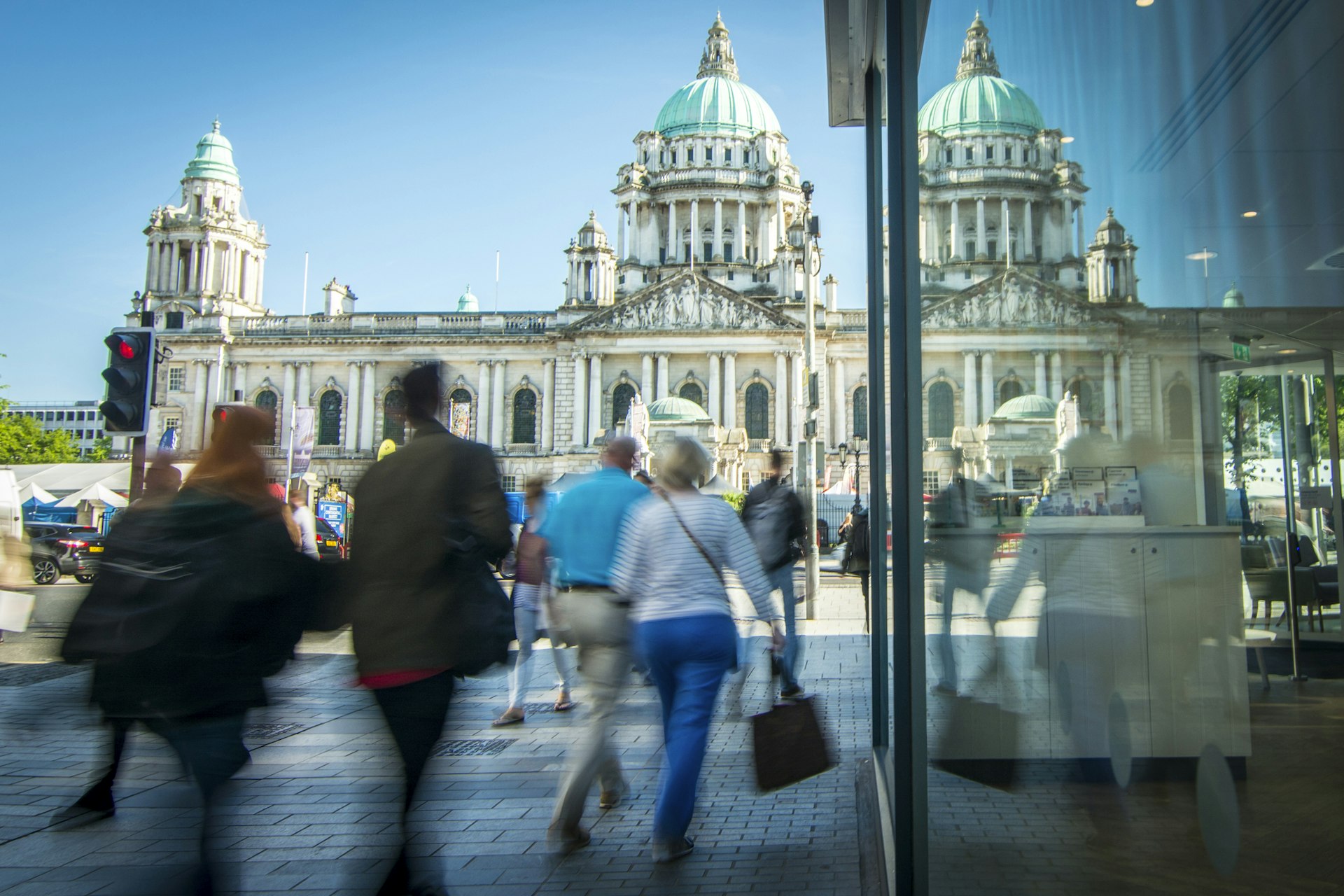 People walking down a pedestrianised street in front of Belfast City Hall