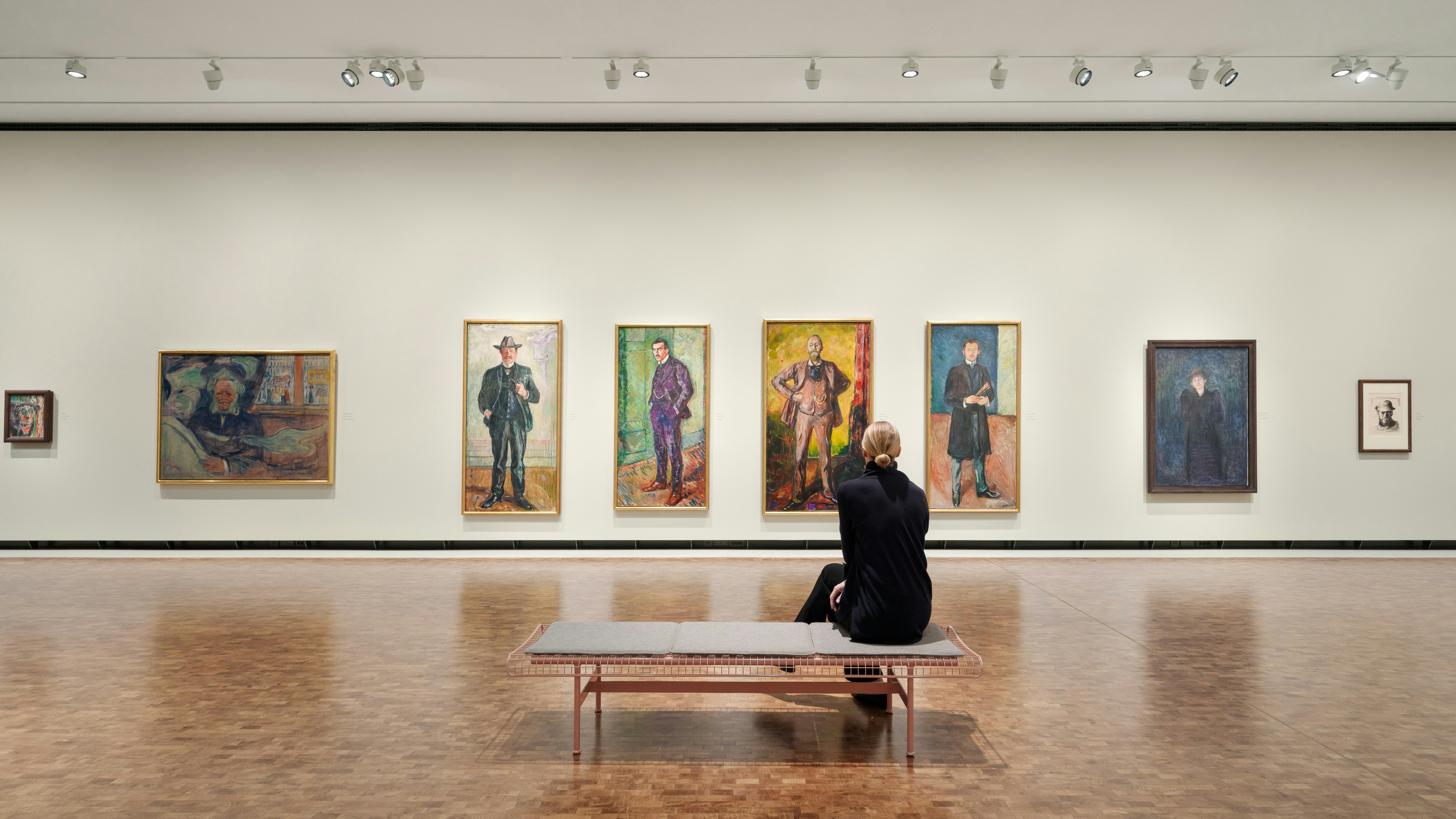 A woman sits down an takes in a series of four paintings on the far wall of the new MUNCH museum in Oslo.