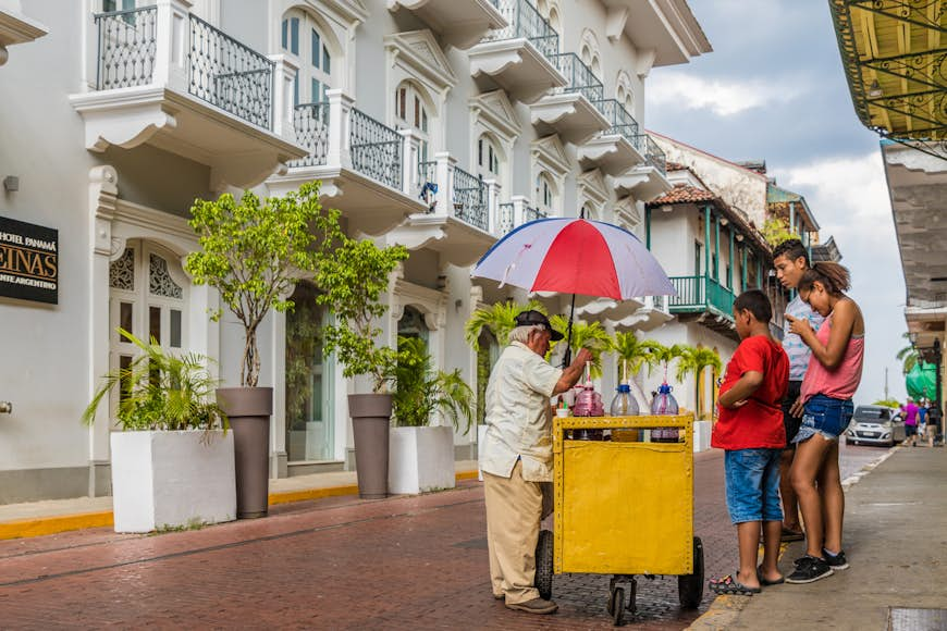 An ice cream seller serving a family from his cart on a quiet cobbled street in Panama City