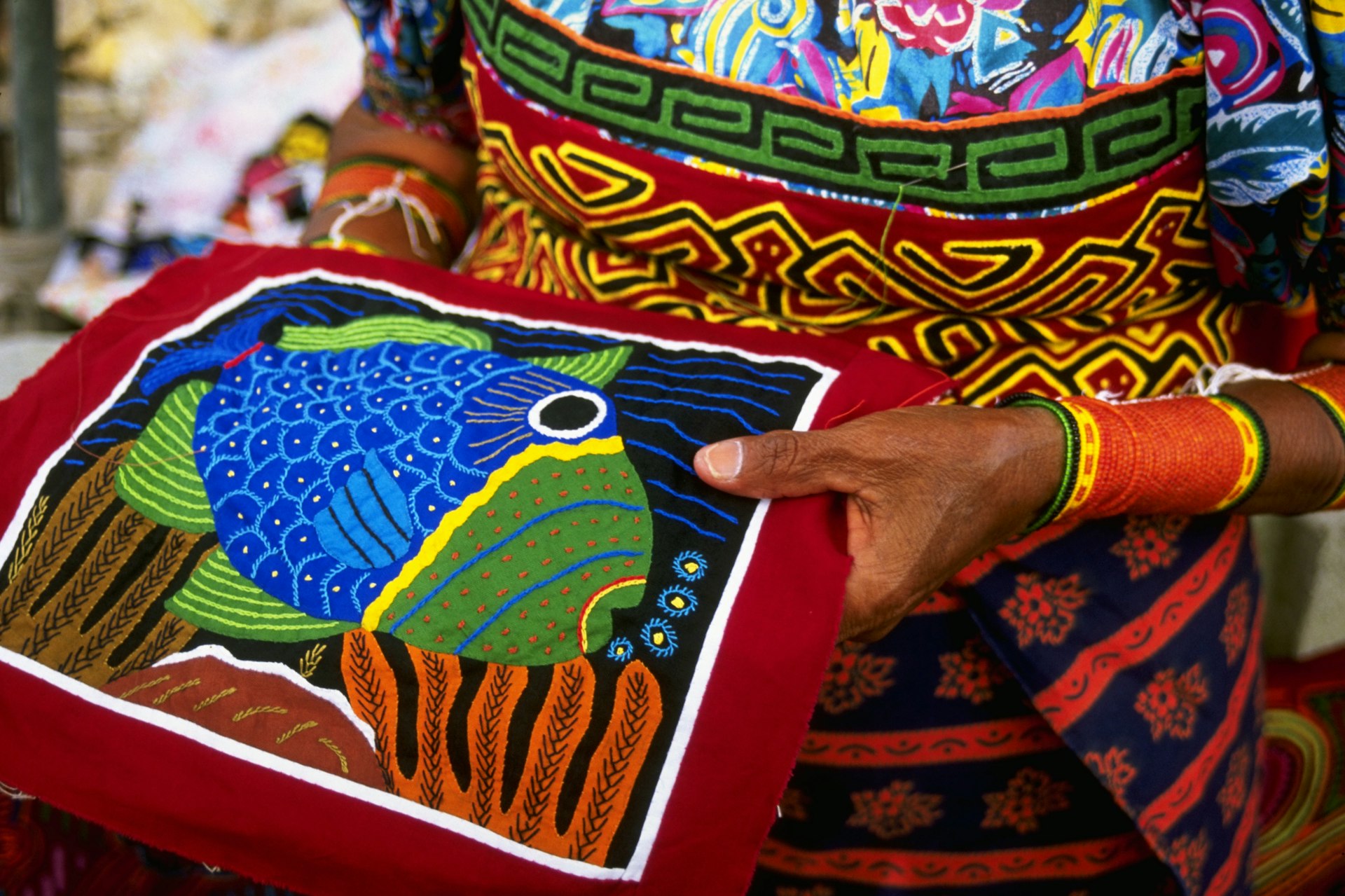 A Panamanian woman holds a handcrafted mola item that she has sewn in Panama City 