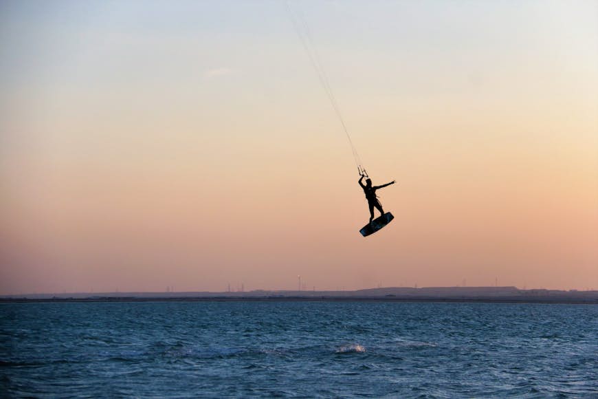 Une personne surfe au coucher du soleil sur une plage au Qatar, péninsule arabique, Moyen-Orient