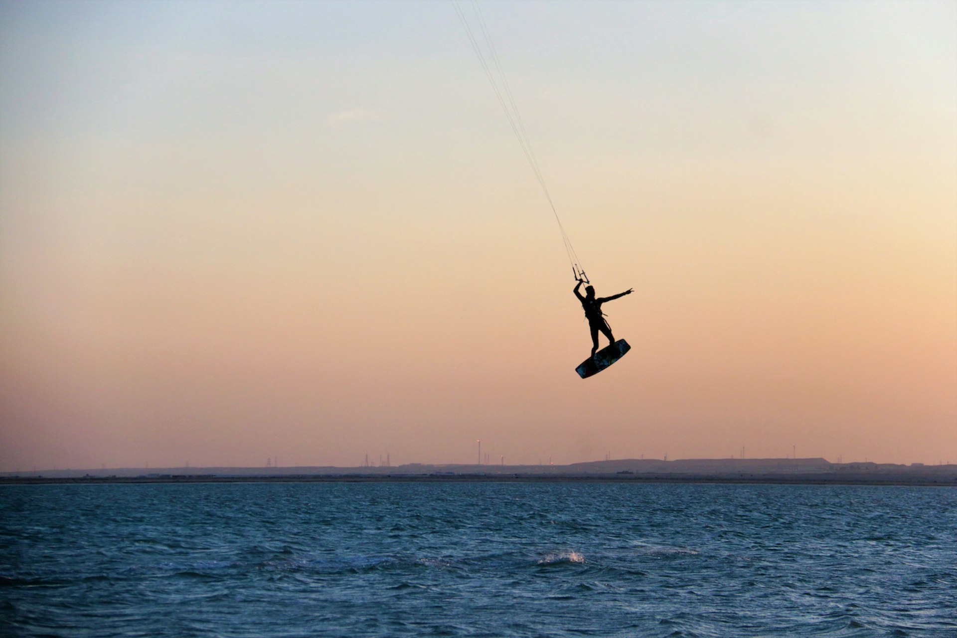 A person kitesurfs at sunset off a beach in Qatar, Arabian Peninsula, Middle East