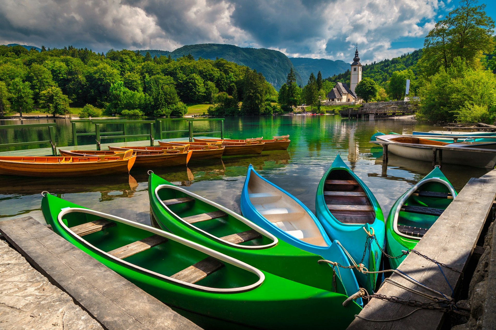 Anchored,Colorful,Canoes,,Kayaks,And,Wooden,Boats,On,The,Lake.