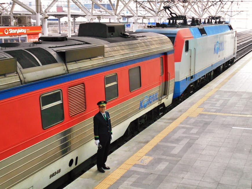 A train conductor stands on the platform in front of the train at a station in Seoul, South Korea.