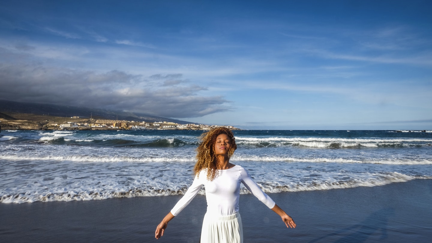 A woman feeling the breeze on a black Tenerife beach