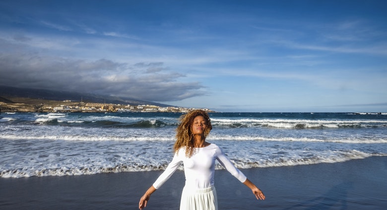 A woman feeling the breeze on a black Tenerife beach