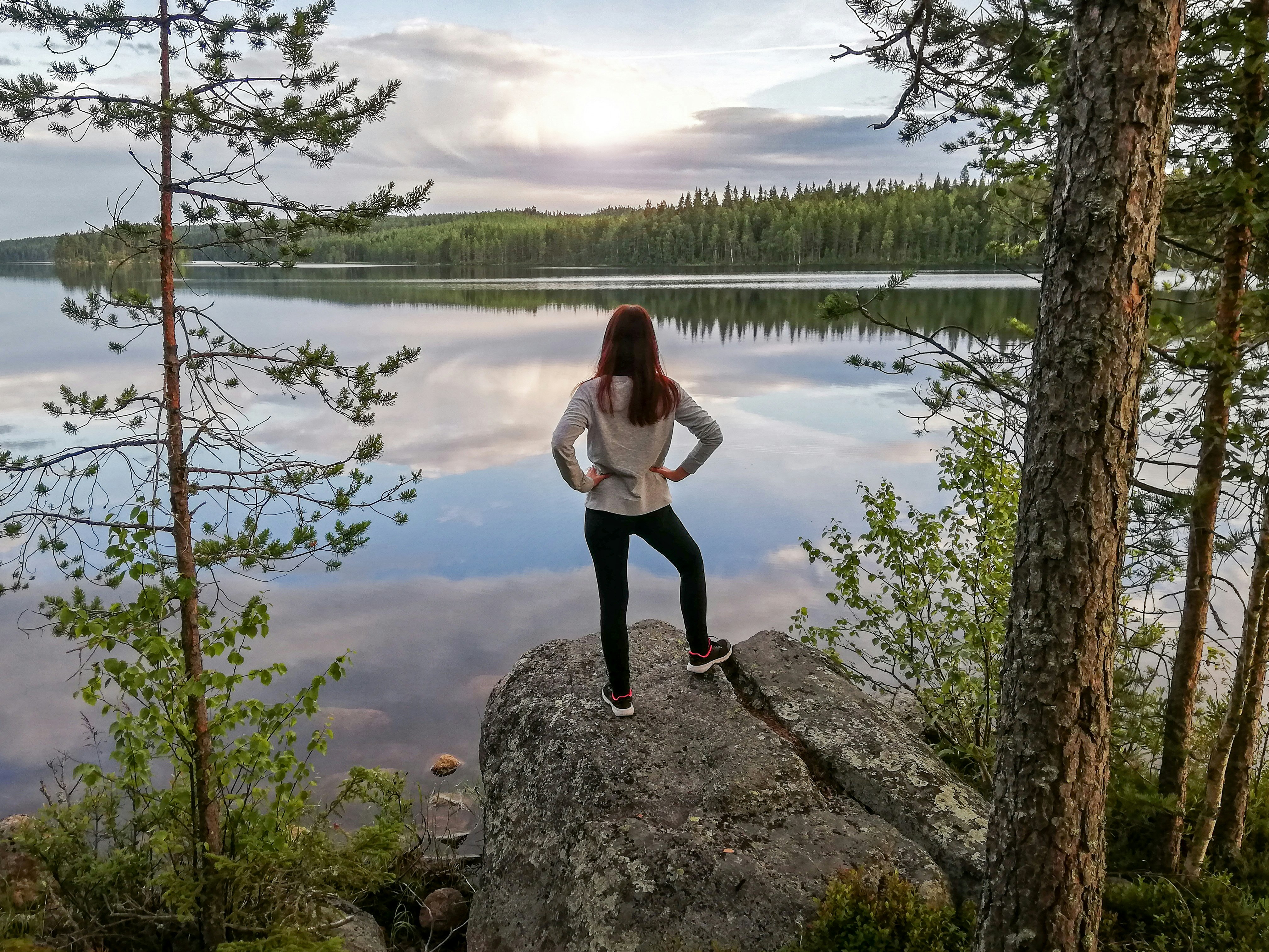 A woman runner standing on a lake shore in north Sweden